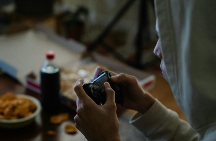 crop gamer with console controller playing video game in house